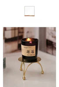 Macro shot of scented candle in dark brown glass on a gold metal tripod stand