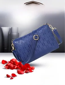 Detailed view of the dark blue embossed pattern and gold hardware on the shoulder bag
