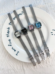 Collection of four elegant square dial ladies watches with metal mesh straps on a plate