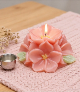 Primer plano de una vela aromática con forma de flor rosa encendida en un tapete