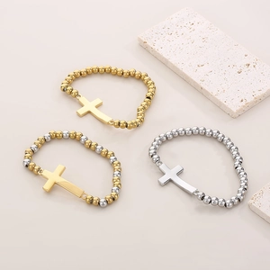 Détail de bracelets perlés avec croix en métal poli en finitions dorée et argentée