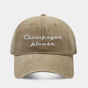 Detail showing the white embroidered Champagne please text on a khaki vintage baseball cap