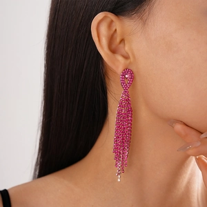 Detail of rose pink long tassel rhinestone earrings worn by a model on side profile