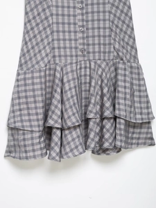 Detail of plaid dress hem featuring double-layered ruffles and decorative buttons