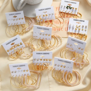 Detailed close-up of gold metal and pearl earring set displayed on elegant beige fabric