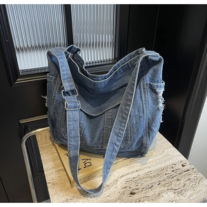 Gros plan détaillé du sac en denim bleu délavé avec bords effilochés et boucle en métal