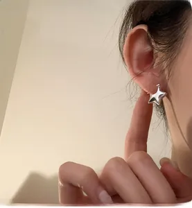 Dettaglio degli orecchini a stella in argento lucido con design bombato e finitura a specchio