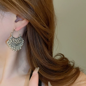 Close-up of vintage silver geometric earring with intricate granulated texture on model