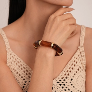 Detail of amber resin bamboo bracelet showing golden metal links on a model's wrist