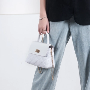 White quilted crossbody bag with gold chain strap and turn-lock closure on female model