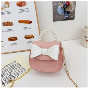 Detail of pink mini bag with pearl handle, large white bow, and golden chain strap