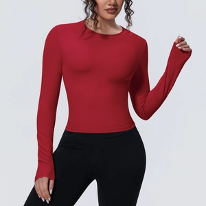 Détail du haut de yoga rouge ajusté avec passe-pouces et leggings de sport noirs