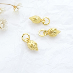 Three gold lotus bud pendants with vertical stripes on textured white paper background