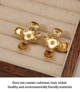 Détail de boucles d'oreilles fleurs dorées à double couche avec centre mat sur velours
