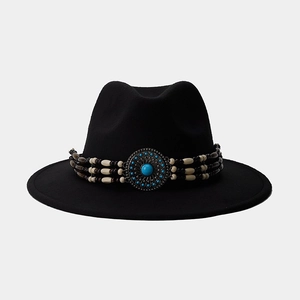 Détail d'un chapeau fedora noir à larges bords avec bande perlée ethnique et boucle métal