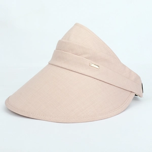 Detail view of the wide brim and decorative gold metal plaque on the beige sun visor hat