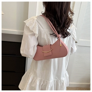 Pink crescent underarm bag with gold hardware worn over a white ruffled dress