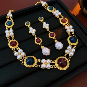Detailed view of vintage jewelry set with pearls and multi-color gems on black tray