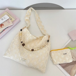 Detail of cream floral textured shoulder bag and matching pouch with beaded strap