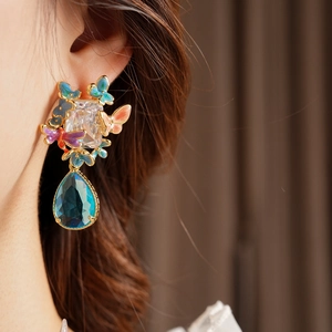 Detail of vintage earring featuring zirconia and colorful enamel butterflies on ear