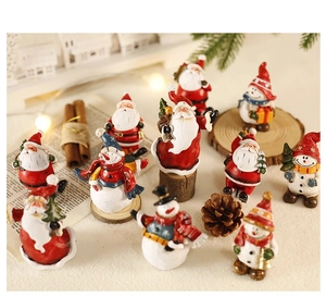 Miniatur-Weihnachtsmann- und Schneemannfiguren aus Harz auf einer gemütlichen Wintertafel