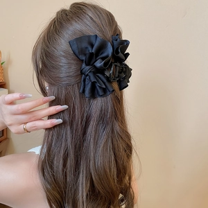 Elegant black fabric bow hair claw clip styled on long brown wavy hair for women