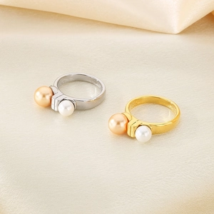 Detailed view of gold and silver stainless steel rings with pearls on silk background