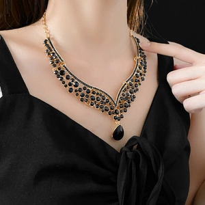 Detail of V-shaped gold necklace with black crystals and a large teardrop pendant