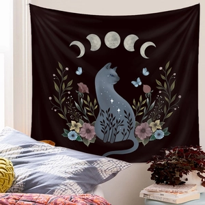 Detail of artistic black tapestry featuring cat silhouette and moon phases on bedroom wall