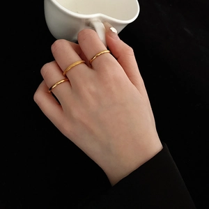 Close-up of three-piece 18K gold minimalist rings with polished and frosted finishes