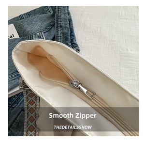 Detail showing smooth silver metal zipper and fine stitching on white canvas tote bag