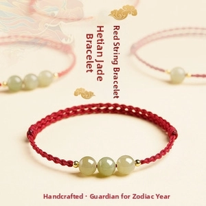 Macro shot of three green Hetian jade beads on a handcrafted red braided rope bracelet