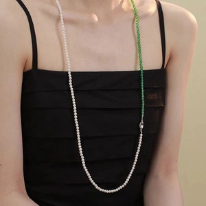 Detail of multi-style long necklace with white pearls and green agate beads on a model