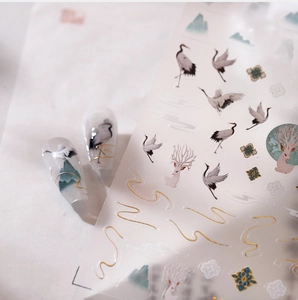 Detail of Chinese style nail stickers featuring cranes and mountains with gold foil accents