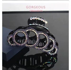 Detailed macro view of large black hair claw clip with colorful gradient rhinestones