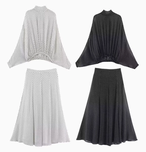 Flat lay of polka dot sets with high neck batwing tops and A-line midi skirts in black and white