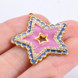 Star-shaped gold pendant with pink and blue enamel and white zircon stones in hand
