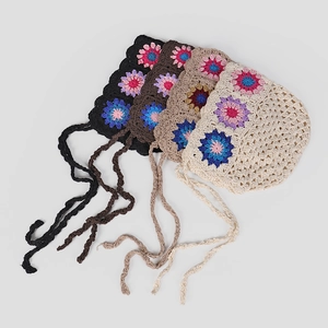 Detail of crochet hollow flower beanies in four colors with long handmade straps