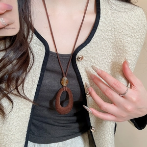 Detail of vintage flocking resin oval pendant on long brown suede cord necklace