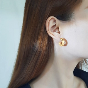 Close-up of elegant gold hollow C-shaped moon earrings worn by a model in cold light