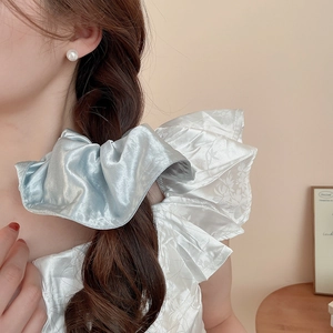 Detail of light blue satin oversized scrunchie on a ponytail for an elegant look