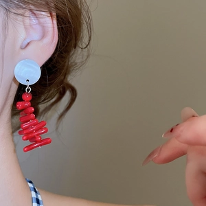 Close-up of elegant red beaded fringe earrings worn by a model in soft natural light