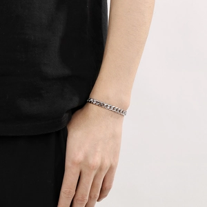 Close-up of a silver cuban link chain bracelet on a male wrist with clean background