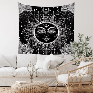 Bohemian sun and moon tapestry in black and white hanging over a modern sofa
