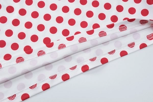 Vue macro détaillée d'un tissu blanc à pois rouges avec une couture à double aiguille soignée