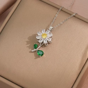 Close-up of small daisy necklace with white petals and yellow heart on silver chain