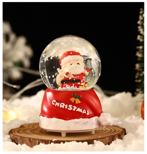 Détail d'une boule à neige de Noël avec figurine Père Noël et base de chapeau rouge