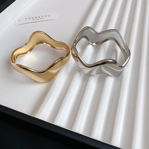 Detail of irregular wave bracelets in gold and silver with high-polish mirror finish