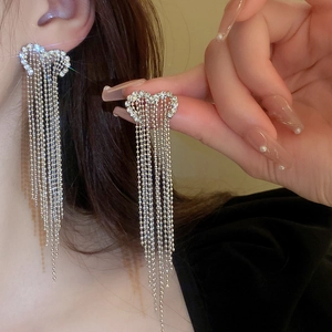 Close-up of sparkling heart-shaped stud earrings with long silver bead chain tassels