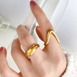 Detail of layered gold curved dome ring and minimalist wavy band on model fingers